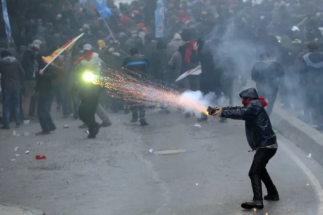A protester uses fireworks during clashes with riot police at the funeral of Berkin Elvan on March 12, 2014 in Istanbul. Riot police fired tear gas and water cannon at protesters in Ankara and Istanbul on Wednesday as tens of thousands took to the streets to mourn a teenage boy who died from injuries suffered in last year's anti-government protests. In the Turkish capital, police clashed with demonstrators as they tried to stop traffic, making a number of arrests and leaving several injured. (Photo by Ozan Kose/AFP Photo)