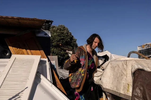 Jaz, a volunteer who lives in their car nearby, helps at an encampment of homeless people near the Nimitz Freeway in Oakland after the city issued an order to remove and clean up the area, April 2, 2024. (Photo by Carlos Barria/Reuters)