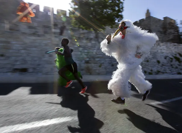 Street performers run along next to a marathon contestant as they pass the Old City walls and the Tower of David complex (R) during the 4th annual Jerusalem Marathon, 21 March 2014. Some 25,000 runners from 54 countries took part in the Marathon, the half-marathon, a 10 kilometers run and special runs in bright, crisp weather. (Photo by Jim Hollander/EPA)