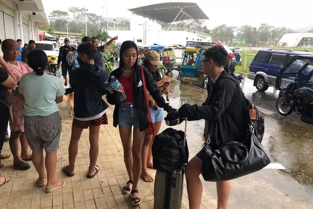 Local tourists with their belongings arrive to take shelter at a sports complex turned into an evacuation center in Dapa town, Siargao island, Surigao del Norte province in southern island of Mindanao on December 16, 2021, as Typhoon Rai barrel the island. (Photo by Roel Catoto/AFP Photo)