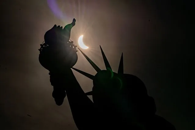 The Statue of Liberty is seen during a partial solar eclipse, where the moon partially blocks out the sun, at Liberty Island in New York City on April 8, 2024. (Photo by David Dee Delgado/Reuters)