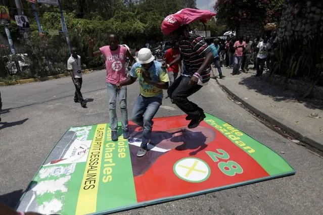 Supporters of PHTK political party jump on a sign of presidential candidate Moise Jean-Charles after breaking it apart during a demonstration to demand the resumption of a postponed presidential runoff election in in Port-au-Prince, Haiti, April 12, 2016. (Photo by Andres Martinez Casares/Reuters)