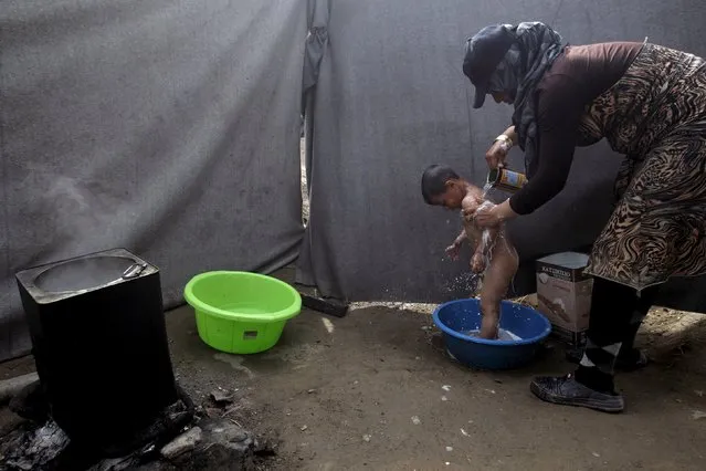 A woman washes her child at a makeshift camp for migrants and refugees at the Greek-Macedonian border near the village of Idomeni, Greece, April 24, 2016. (Photo by Alexandros Avramidis/Reuters)