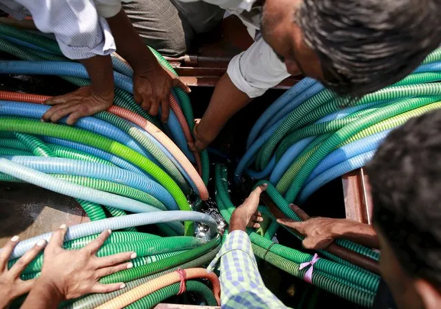 Residents hold plastic hoses as they fetch water from a government-run water tanker in Masurdi village, in Latur, India, April 16, 2016. (Photo by Danish Siddiqui/Reuters)