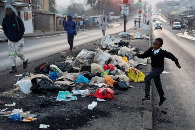 A young girl makes her way to school by walking past piles of uncollected trash in the township of Alexandra, a day before the national election in Johannesburg, South Africa on May 28, 2024. (Photo by Ihsaan Haffejee/Reuters)