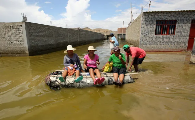 Residents use a raft to cross a flooded street , after rivers breached their banks due to torrential rains, causing flooding and widespread destruction in Huarmey, Ancash, Peru, March 22, 2017. (Photo by Mariana Bazo/Reuters)
