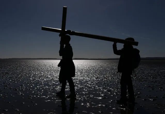Pilgrims walk across a tidal causeway while carrying a cross during the final leg of the Northern Cross pilgrimage to Holy Island in Northumbria, Britain, March 25, 2016. For forty one years Christians have taken part in the pilgrimage to Holy Island, walking through Northumberland and the Scottish Borders, during Holy Week. (Photo by Nigel Roddis/EPA)