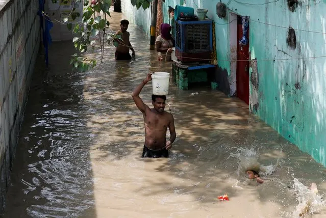 A man carries a water bucket as he wades through a flooded lane on the banks of the river Yamuna in Delhi, India, August 21, 2019. (Photo by Anushree Fadnavis/Reuters)