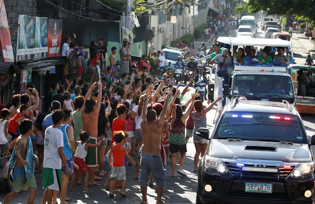 Supporters wave at the motorcade of Presidential candidate Jejomar Binay and Filipino boxer and Senatorial candidate Manny Pacquiao during election campaigning in Malabon Metro Manila in the Philippines May 6, 2016. (Photo by Erik De Castro/Reuters)