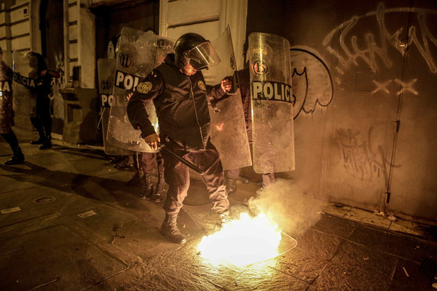 A policeman tries to put out a fire on a shield of the security forces, during an anti-government mobilization in the historic center of Lima, which brought together thousands of Peruvians who demanded the resignation of President Dina Boluarte, in Lima, Peru, 09 February 2023. The Peruvian National Police (PNP) deployed nearly 10,000 agents as the protest strike demanded the resignation of Boluarte, a transitional government with the election of new leadership in Congress, and a referendum for a new constitution to replace the current one, which was drawn up in 1993 under the government of former President Alberto Fujimori (1990-2000). (Photo by EPA/EFE/Stringer)