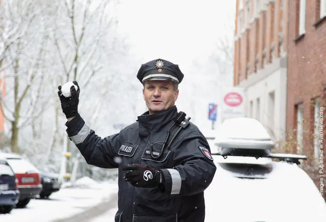 A police officer holds a snowball in his hand