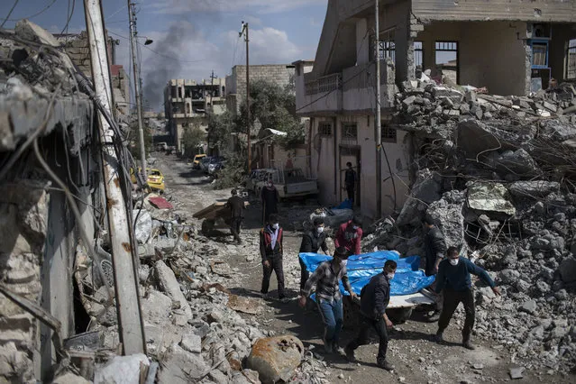 In this Friday, March 24, 2017 file photo, residents carry the body of several people killed in airstrikes during fighting between Iraq security forces and Islamic State on the western side of Mosul, Iraq. The March 17 explosion that leveled the building in the district of New Mosul killed more than 100 people as Iraqi forces were battling Islamic State group militants in the area. The U.S.-led coalition acknowledged there was an airstrike against the building. But U.S. military officials have said the munitions used were not enough to bring down the structure and have suggested IS militants herded people inside, booby-trapped the building and then lured an airstrike. (Photo by Felipe Dana/AP Photo)