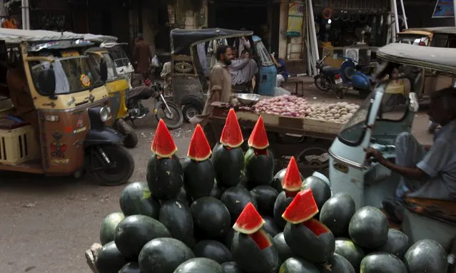 Vehicles move past watermelons, displayed for sale from a cart, along a street at a neighborhood in Karachi, Pakistan, April 19, 2016. (Photo by Akhtar Soomro/Reuters)