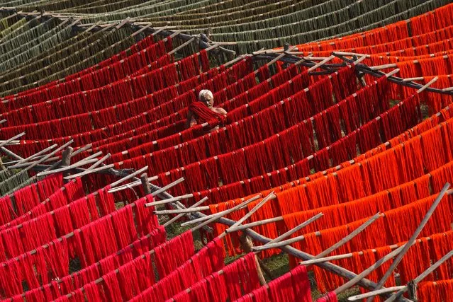 An Indian laborer hangs dyed yarn for drying under the sun at a textile mill in Mangalagiri near Vijayawada, in the southern state of Andhra Pradesh, India, 08 February 2022. (Photo by Idrees Mohammed/EPA/EFE)