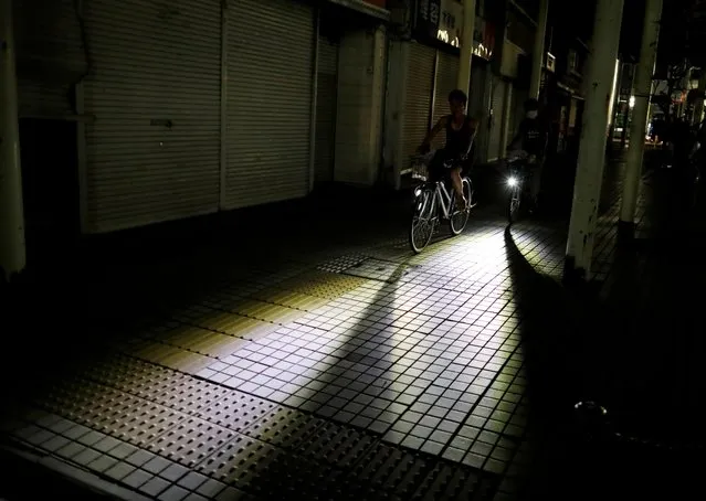 Men ride bicycles along a sidewalk during a blackout caused by Typhoon Faxai near a train station in Kisarazu, Chiba prefecture, Japan on September 9, 2019. (Photo by Issei Kato/Reuters)