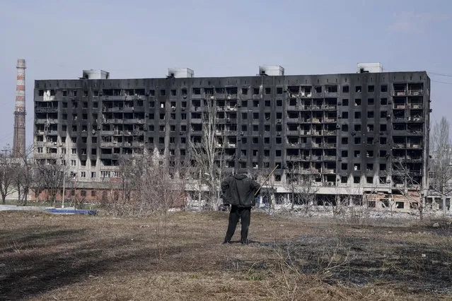 A man looks at a burned apartment building that was damaged by shelling in Mariupol, Ukraine, Sunday, March 13, 2022. (Photo by Evgeniy Maloletka/AP Photo)
