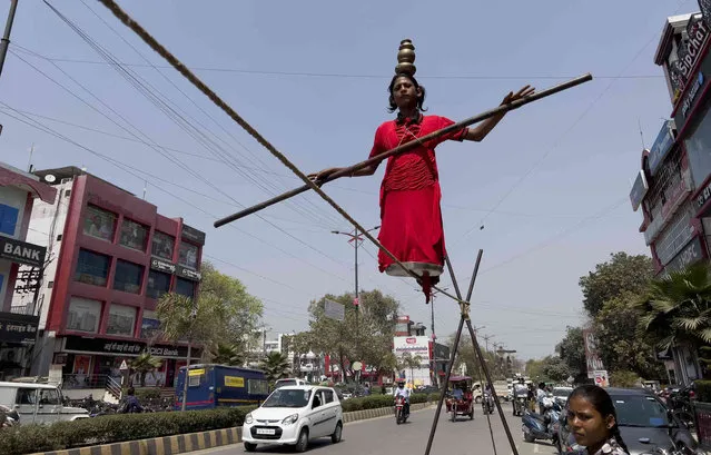 A girl walks a tight rope as she performs at a street to attract alms in Prayagraj, Uttar Pradesh state, India, Tuesday, March 15, 2022. (Photo by Rajesh Kumar Singh/AP Photo)