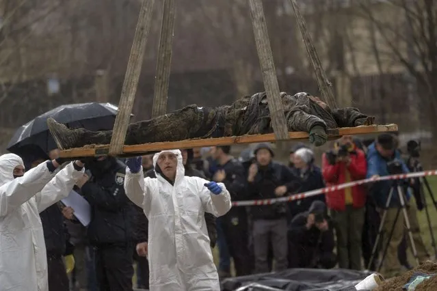 Forensic workers carry the corpse of a civilian killed during the war against Russia after collecting it from a mass grave in Kyiv, Ukraine, Friday, April 8, 2022. (Photo by Rodrigo Abd/AP Photo)