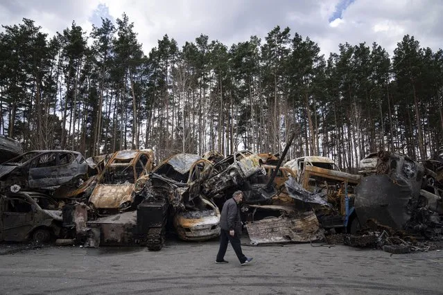 A man walks past a storage place for burned armed vehicles and cars, on the outskirts of Kyiv, Ukraine, Monday, April 11, 2022. (Photo by Evgeniy Maloletka/AP Photo)