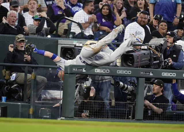 Los Angeles Dodgers third baseman Justin Turner tumbles over the railing to the third-base photo well to haul in a foul pop off the bat of Colorado Rockies' Charlie Blackmon in the fifth inning of a baseball game Saturday, April 9, 2022, in Denver. (Photo by David Zalubowski/AP Photo)