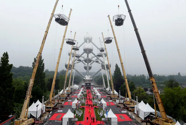 Ten tables, accommodating a total of 220 guests, are suspended from cranes at a height of 40 metres in front of the Atomium, a 102-metre (335 feet) high structure and its nine spheres, built for the 1958 Brussels World's Fair, as part of the 10th anniversary of the event known as “Dinner in the Sky”, in Brussels, Belgium June 1, 2016. (Photo by Yves Herman/Reuters)