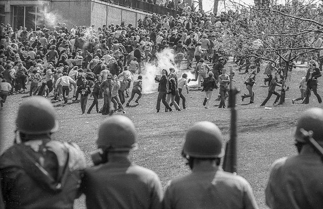 View, from behind, as Ohio National Guardsmen in gas masks and with rifles as they prepare to advance up Blanket Hill, through clouds of teargas, to drive back Kent State University students during an antiwar demonstration on the university's campus, Kent, Ohio, May 4, 1970. Visible at left is Taylor Hill. The protests, initially over the US invasion of Cambodia, resulted in the deaths of four protesters (and the injuries of nine others) after the National Guard opened fire on students. (Photo by Howard Ruffner/Getty Images)