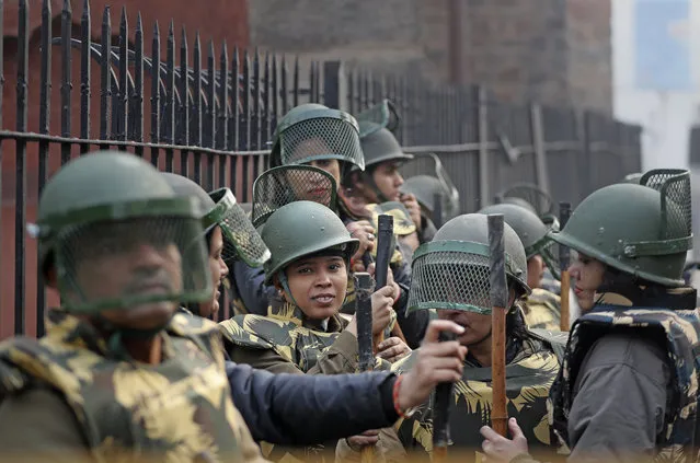 Indian police personnel stand guard at a barricade as Indians protest against the Citizenship Amendment Act in New Delhi, India, Friday, December 20, 2019. Police banned public gatherings in parts of the Indian capital and other cities for a third day Friday and cut internet services to try to stop growing protests against a new citizenship law that have left eight people dead and more than 4,000 others detained. (Photo by Altaf Qadri/AP Photo)