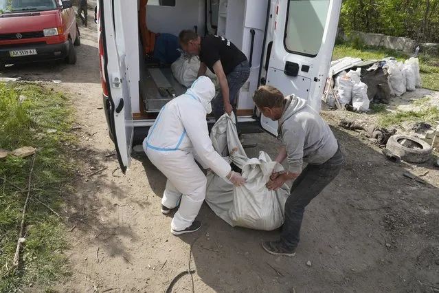 Volunteers move a body of a killed Russian soldier during the exhumation in the village of Malaya Rohan, on the outskirts of Kharkiv, Thursday, May 19, 2022. (Photo by Andrii Marienko/AP Photo)