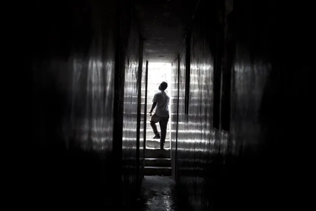 In this June 29, 2015 photo, a young man walks to an upper level inside an earthquake-damaged building where young men are squatting in central Port-au-Prince, Haiti. At night, damaged but intact buildings serve as homes to some of the many still left homeless after the 2010 earthquake, even if the structures lack water and other amenities. (Photo by Rebecca Blackwell/AP Photo)