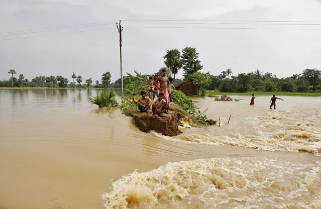 Flood-affected people sit on a broken embankment of a road damaged by the flood waters as they wait for relief supplies at Howrah district in West Bengal, India, August 5, 2015. (Photo by Rupak De Chowdhuri/Reuters)