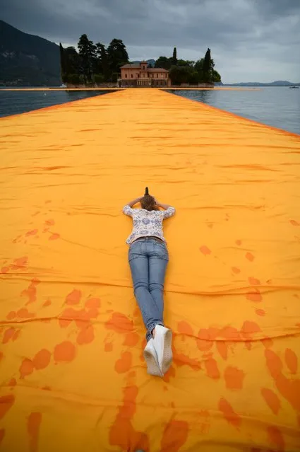 A woman takes pictures of the monumental installation “The Floating Piers” created by Artist Christo Vladimirov Javacheff and Jeanne-Claude, on June 16, 2016 during a press preview at the lake Iseo, northern Italy. Some 200,000 floating cubes create a 3-kilometers runway connecting the village of Sulzano to the small island of Monte Isola on the Iseo Lake for a 16-day outdoor installation opening on June 18. (Photo by Filippo Monteforte/AFP Photo)