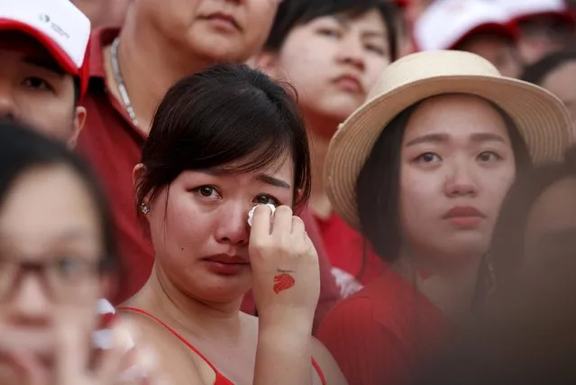 A woman cries as she watches a video tribute to the late former prime minister Lee Kuan Yew during Singapore's Golden Jubilee parade at Padang near the central business district August 9, 2015. (Photo by Edgar Su/Reuters)