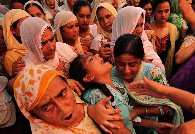 Relatives console the daughter (C) of Ranjit Singh, an Indian Army soldier who was killed in a ceasefire violation by Pakistani troops along the Line of Control (LOC) in Kupwara district on Wednesday before his funeral on the outskirts of Jammu July 14, 2017. (Photo by Mukesh Gupta/Reuters)