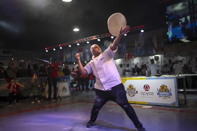 A pizza master performs an exhibition during the Argentine Pizza Championship in Buenos Aires, Argentina, Tuesday, June 7, 2022. (Photo by Rodrigo Abd/AP Photo)