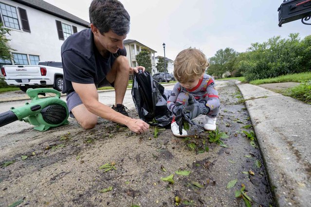 John Finney and his son Gabriel, 2, using gloves, clean up debris after Hurricane Francine near their home in Kenner, La., in Jefferson Parish, Thursday, September 12, 2024. (Photo by Matthew Hinton/AP Photo)