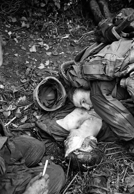 A U.S. Marine listens for the heartbeat of a dying buddy who suffered head wounds when the company's lead platoon was hit with enemy machine gun fire as they pushed through a rice paddy just short of the demilitarized zone in South Vietnam Sept. 17, 1966