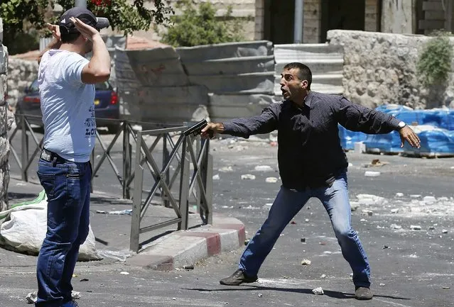 An undercover Israeli police officer gestures with a gun at a Palestinian suspected of throwing stones in the East Jerusalem neighbourhood of Wadi al-Joz during a protest against the Israeli offensive on Gaza July 25, 2014. (Photo by Ammar Awad/Reuters)