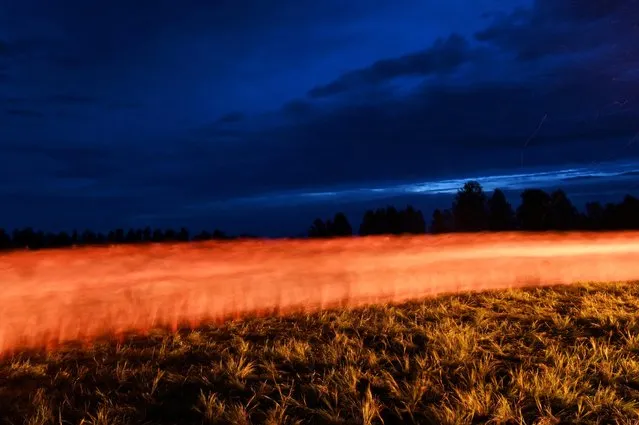People celebrate the summer solstice at a festival in the village of Okunevo in Omsk region, Russia on June 21, 2022. Picture taken with long exposure. (Photo by Alexey Malgavko/Reuters)