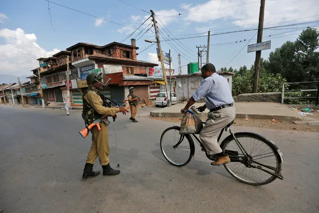 An Indian policeman stops a man riding a bicycle during a curfew in Srinagar July 12, 2016. (Photo by Danish Ismail/Reuters)