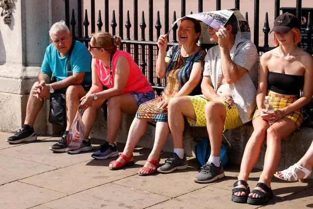 People shelter from the sun underneath a map during the hot weather, outside Buckingham Palace in London, Britain, July 18, 2022. (Photo by John Sibley/Reuters)