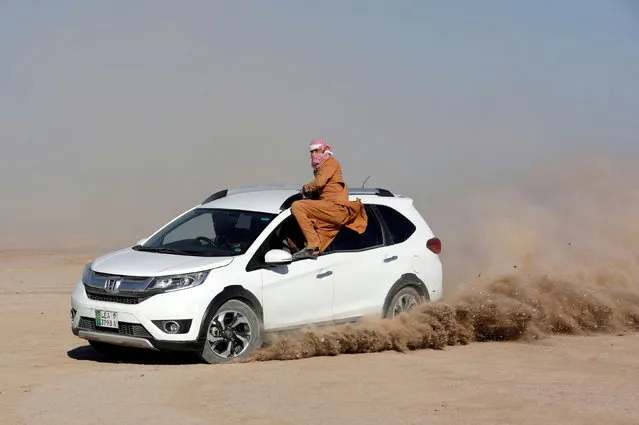 An enthusiast sits on a window of a car performing stunt during the 15th edition of the Cholistan Desert Rally 2020, in Cholistan Desert, Pakistan on February 15, 2020. (Photo by Akhtar Soomro/Reuters)