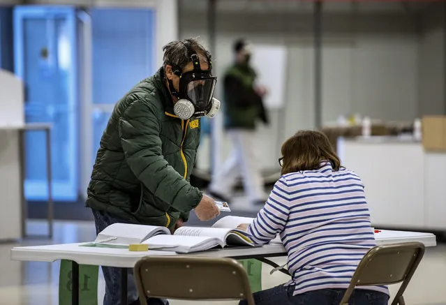 Robert Forrestal, left, wears a full face chemical shield to protect against the spread of coronavirus, as he votes Tuesday, April 7, 2020, at the Janesville Mall in Janesville, Wis. Hundreds of voters in Wisconsin are waiting in line to cast ballots at polling places for the state's presidential primary election, ignoring a stay-at-home order over the coronavirus threat. (Photo by Angela Major/The Janesville Gazette via AP Photo)