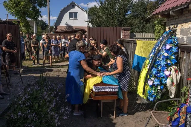 Kateryna (C), the mother of the fallen Ukrainian soldier Andrii Dzyubenko, along with other relatives, friends and comrades, mourns next to the coffin during his funeral ceremony in Bucha, northwest of Kyiv (Kiev), Ukraine, 30 August 2022. Ukrainian soldier Andrii Dzyubenko was killed in a battle near Maryinka, Donetsk region, on 24 August. Russian troops on 24 February entered Ukrainian territory, starting a conflict that has provoked destruction and a humanitarian crisis. (Photo by Roman Pilipey/EPA/EFE)