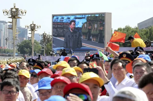 Spectators watch as a big electronic screen displays Chinese President Xi Jinping (back) inspecting the army at the beginning of the military parade marking the 70th anniversary of the end of World War Two, in Beijing, China, September 3, 2015. (Photo by Reuters/China Daily)
