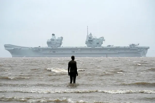 Royal Navy aircraft carrier, HMS Prince of Wales, sails past the statues of “Another Place” as it arrives in Liverpool on February 28, 2020 in Liverpool, England. The Royal Navy's newest aircraft carrier completed its journey from Portsmouth Naval Base to Liverpool in heavy rain and high winds. (Photo by Christopher Furlong/Getty Images)
