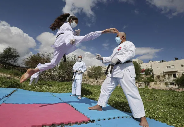 Beesan al-Jubeh, (L), Palestinian under-10 national karate champion, trains with her father Sami (R) and other family members, all wearing face masks and gloves due to the COVID-19 coronavirus pandemic, outside their house in the city of Hebron in the Occupied West Bank on April 9, 2020. (Photo by Hazem Bader/AFP Photo)