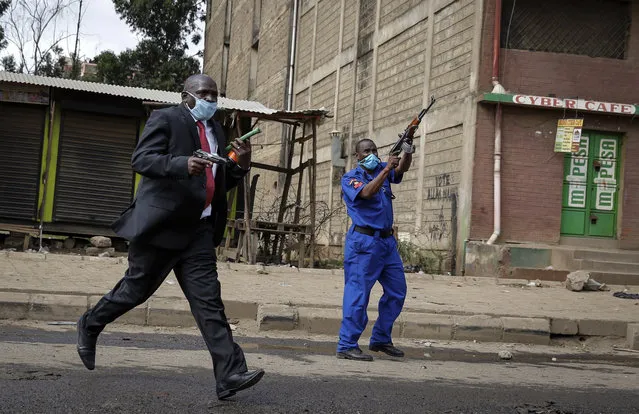 Police officers fire live bullets in the air to disperse protesters in the Kariobangi slum of Nairobi, Kenya Friday, May 8, 2020. Hundreds of protesters blocked one of the capital's major highways with burning tires to protest government demolitions of the homes of more than 7,000 people and the closure of a major food market, causing many to sleep out in the rain and cold because of restrictions on movement due to the coronavirus. (Photo by Brian Inganga/AP Photo)