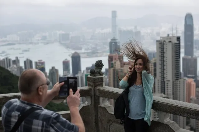 Tourists take photographs from a panoramic lookout on Victoria Peak during windy weather brought by typhoon Khanun in Hong Kong, China, 15 October 2017. The Hong Kong Observatory issued the No 8 storm signal on 15 October as typhoon Khanun was expected to pass within 200km of Hong Kong. (Photo by Erome Favre/EPA/EFE)