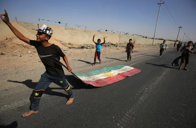 An Iraqi boy drags a Kurdish flag as Iraqi forces advance towards the centre of Kirkuk during an operation against Kurdish fighters on October 16, 2017. Iraqi forces seized the Kirkuk governor's office, key military sites and an oil field as they swept across the disputed province following soaring tensions over an independence referendum. (Photo by Ahmad Al-Rubaye/AFP Photo)