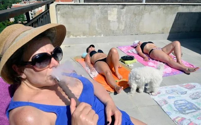 Lebanese women and their dog take advantage of good weather to sunbathe on the rooftop of their home in Mansourieh Village near Beirut, Lebanon, 12 May 2020. during a nationwide coronavirus lockdown. Rooftops, usually a normal place for water tanks, satellites dishes and unwanted home accessories, has become a new place for people seeking social distance and isolation during the pandemic. According to the government's decision, Lebanon will go under full shutdown for four days on 14 until 17 May 2020, as the country recorded a rise in coronavirus cases. (Photo by Wael Hamzeh/EPA/EFE/Rex Features/Shutterstock)